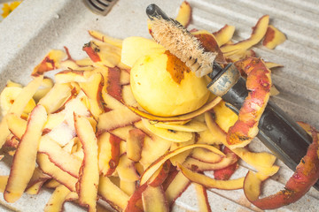 Purified skin of fresh potatoes with special knife on sink.