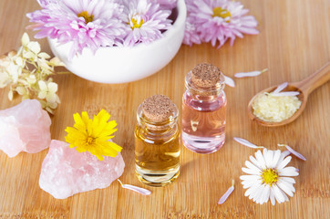 Essential natural oil in medical glass bottles with chrysanthemum flowers and bath salt for SPA and aromatherapy on wooden background