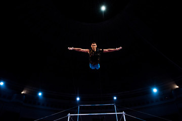 Fototapeta na wymiar athletic gymnast with outstretched hands in arena of circus