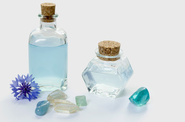 Glass bottles with blue cornflower flower water or essential oil, minerals and plant on white background, SPA or phytotherapy concept