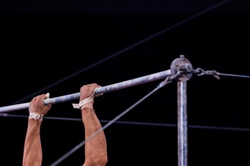 cropped view of athletic gymnast performing on horizontal bars in circus