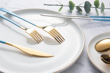 Beautiful golden tableware and plates on marble background