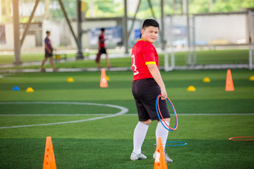 Obraz premium Football players are putting ring ladder marker and football training equipment on green artificial turf. Material for training class of football academy.