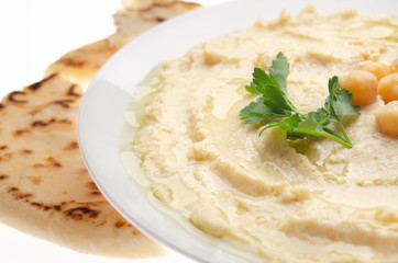 Closeup view at Hummus topped with beans olive oil and green coriander leaves with pita bread