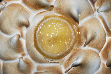Close up of a lemon pie with meringue and a lemon slice on top.