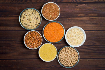grains red lentils, basmati rice, buckwheat, chickpeas, millet in plates. organic healthy cereals. on a wooden background. natural vegetarian vegetable protein . the view from the top. close up