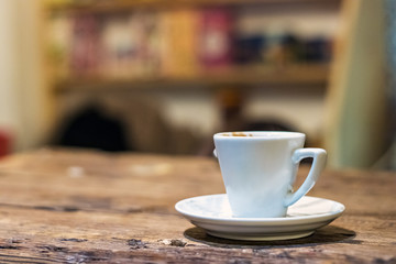 A white coffee espresso cup with plate on a wooden table, indoors.