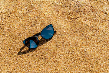Fototapeta na wymiar Shades on yellow sand on the beach. Summer vacation concept. Eyewear protection from UV radiation