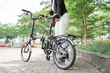 asian woman worker holding her folding bike when go to office