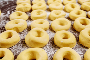 Raw round donuts on table with flour before frying.