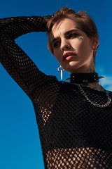 Urban Style. Young stylish woman in choker standing outdoors looking aside pensive bottom view...