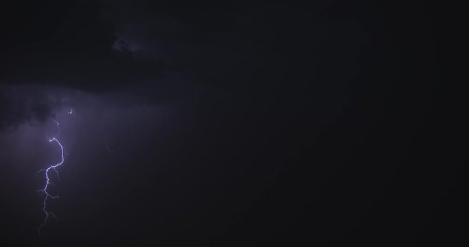 View of lightning strikes on night dark sky in summer. Stormy sky with lightning flashing and thunder. Night thunderstorm clouds. BMPCC 4K