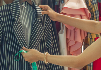 The hands of an Asian girl designer are using a tape measure. Measure the length, the proportion of...