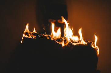 Black veiled woman burns the newspaper on a dark background.