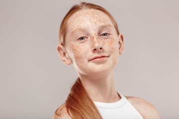Inclusive Beauty. Girl with freckles standing isolated on grey smilign confident bottom view