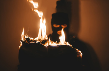 Beautiful desperate young woman wearing black hijab  burns the paper. Selective focus in flame
