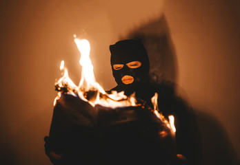 Beautiful desperate young woman wearing black hijab  burns the newspaper.