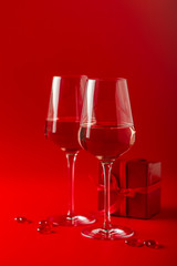 Two full glasses of wine over red background