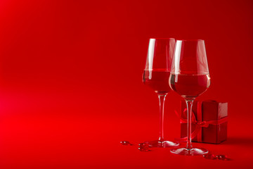 Two full glasses of wine over red background