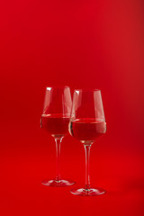 Two full glasses of wine over red background
