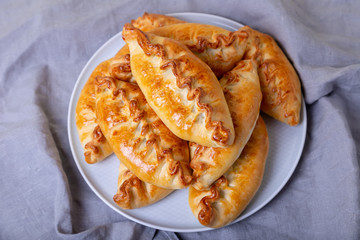 Pies (pirozhki) with cabbage. Homemade baking. Traditional Russian and Ukrainian cuisine. In the background is a dish with pies. Close-up.