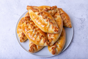 Pies (pirozhki) with cabbage. Homemade baking. Traditional Russian and Ukrainian cuisine. In the background is a dish with pies. Close-up.