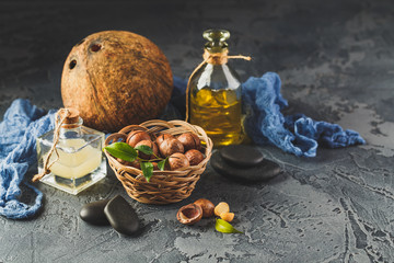 Natural macadamia and coconut oil in aglass bottles with macadamia nuts on wooden board