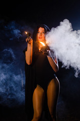 Fototapeta na wymiar Young girl in a long black coat fire night.