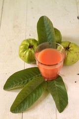 A glass of Guava Juice with fresh Guava fruit slices isolated on wooden background