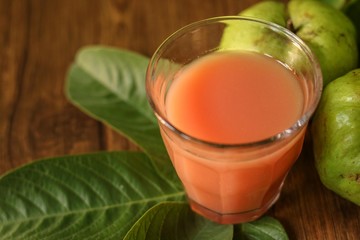 A glass of Guava Juice with fresh Guava fruit slices isolated on wooden background