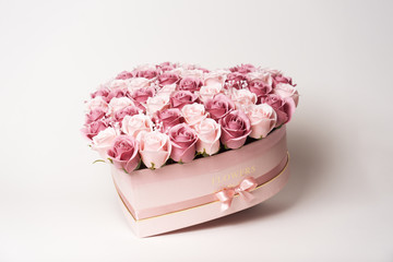 Flowers in bloom: A large bouquet of pink and white roses in a box in the shape of a heart on a white background.