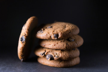 Macro shot of several chocolate chip cookies with pieces of chocolate on a dark background