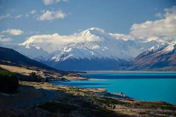 Snow covered Mount Cook with Lake Pukaki in the foreground and blue sky and white clouds, South Island, New Zealand