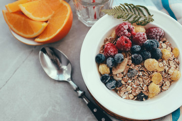 Healthy breakfast: oatmeal with  raspberries,oranges and blueberries. Homemade granola. Healthy breakfast ingredients. Bowl of oat granola with milk, fresh fruit. Top view, copy space
