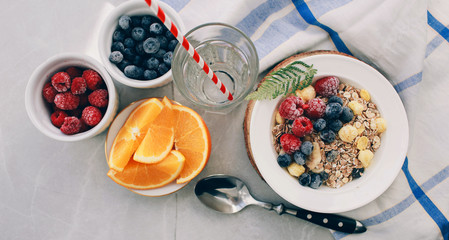 Healthy breakfast: oatmeal with  raspberries,oranges and blueberries. Homemade granola. Healthy breakfast ingredients. Bowl of oat granola with milk, fresh fruit. Top view, copy space