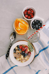 Healthy breakfast: oatmeal with  raspberries,oranges and blueberries. Homemade granola. Healthy breakfast ingredients. Bowl of oat granola with milk, fresh fruit. Top view, copy space