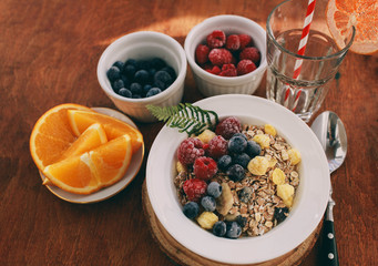 Healthy breakfast: oatmeal with  raspberries,oranges and blueberries. Homemade granola. Healthy breakfast ingredients. Bowl of oat granola with milk, fresh fruit. Top view, copy space