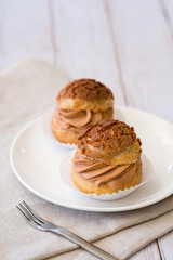 Homemade choux cream or cream puffs with tea cream on wooden background.