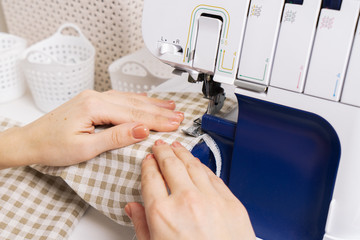 Women at work: a dressmaker girl makes a seam on a sewing machine.