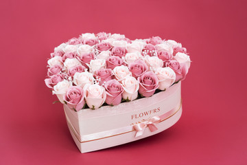 Flowers in bloom: A large bouquet of pink and white roses in a box in the shape of a heart on a pink background.