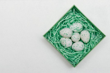 Easter decoration - foam eggs lie in a box with paper ribbons on a felt background. Background for inscriptions or postcards. Materials for needlework and creativity.