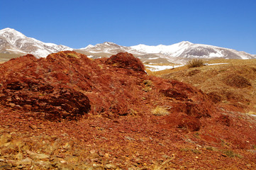 Natural red mountains and snow peaks in Kyzyl-Chin valley, also called as Mars valley. Altai, Siberia, Russia