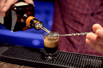 Young bartender carefully makes an alcoholic drink at the bar