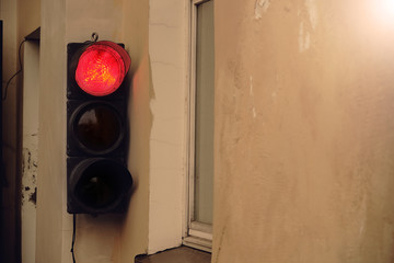 Old street traffic light hanging on wall near a window