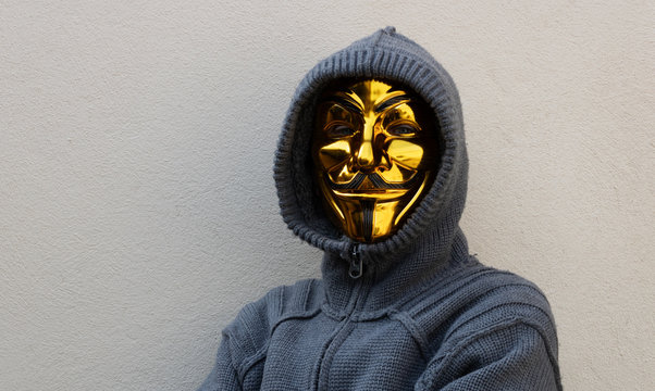 Velvary, CZECH REPUBLIC &ndash; February 27, 2019: An unidentified man is wearing the Vendetta mask and standing in front of a wall, the mask is a symbol of a hackers group Anonymous
