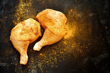 Raw chicken meat on a dark concrete table isolated background. Two raw chicken thighs, smeared with...