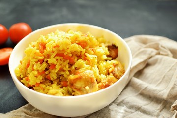 Basmati rice with chicken and carrots. Spicy rice with turmeric, in a white plate, bowl. Side view
