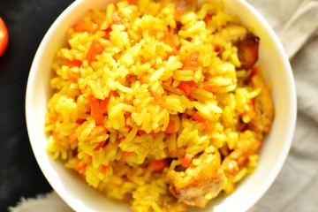 Basmati rice with chicken and carrots. Spicy rice with turmeric, in a white plate, bowl. View from above. Top view.