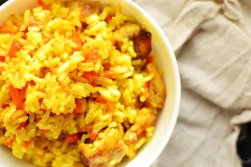 Basmati rice with chicken and carrots. Spicy rice with turmeric, in a white plate, bowl. View from above. Top view.