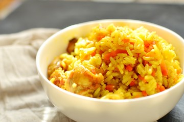 Basmati rice with chicken and carrots. Spicy rice with turmeric, in a white plate, bowl. Side view